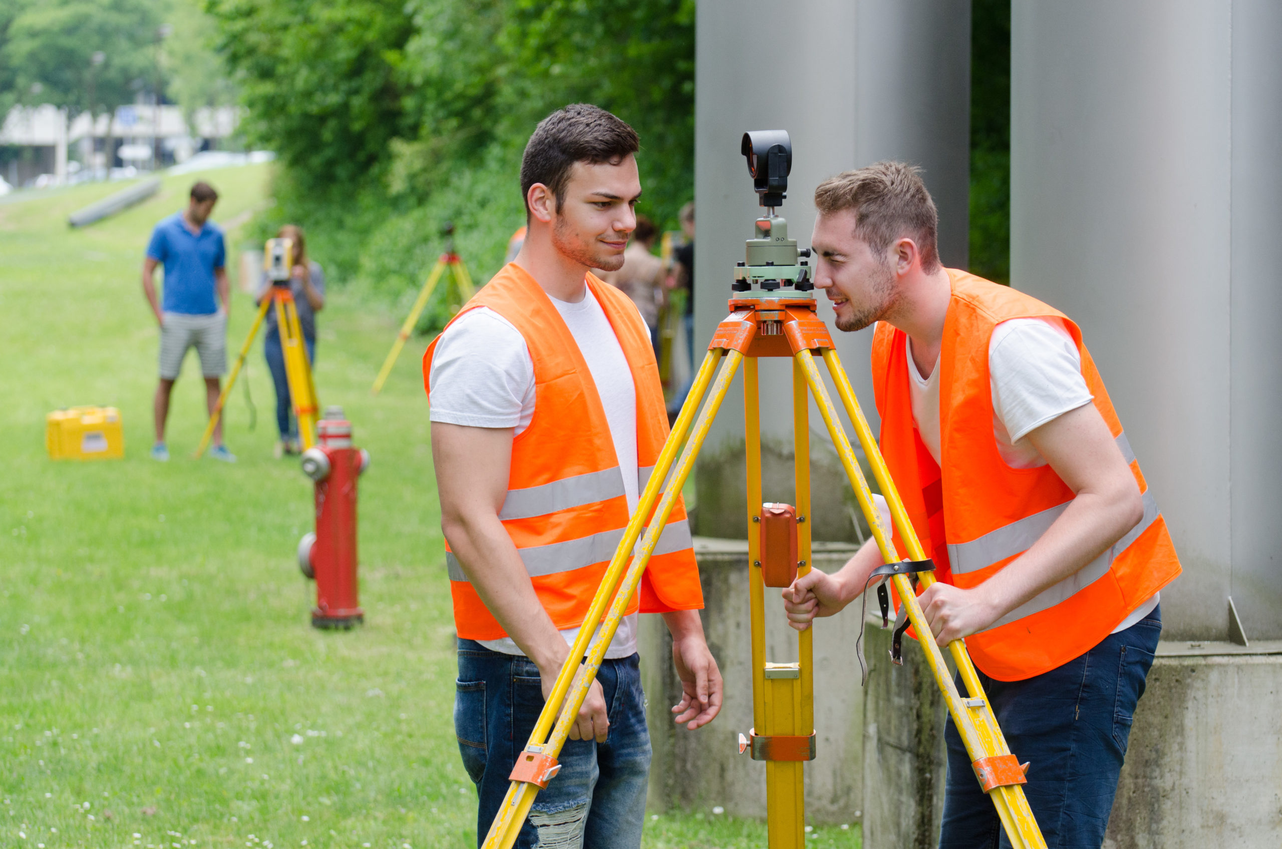 2 Auszubildende der Vermessungstechnik bei der Arbeit.